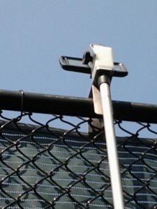 Smartphone mounted on fence from outside the court